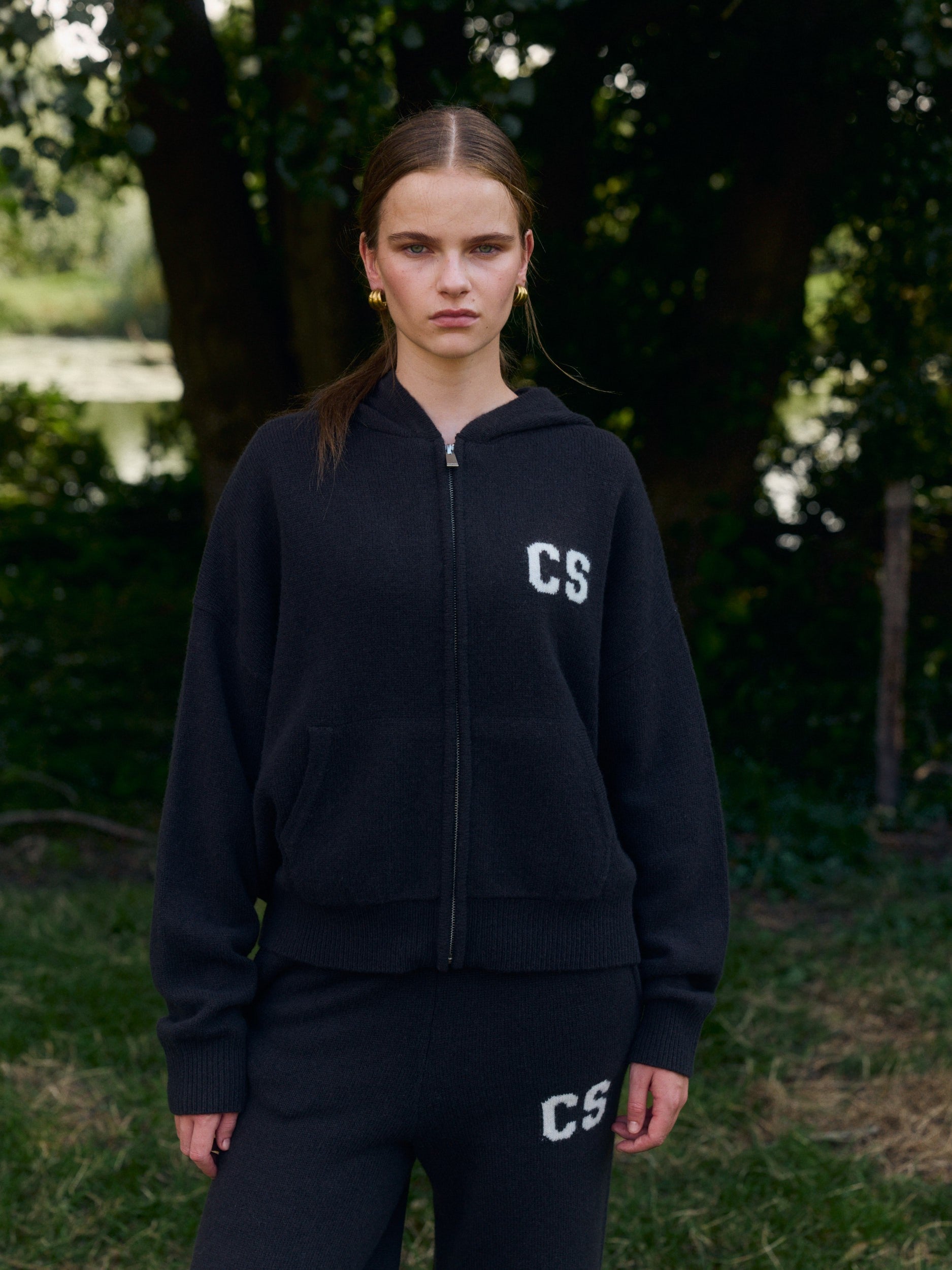 Woman wearing a dark brown wool knit zip jacket and matching pants outdoors.